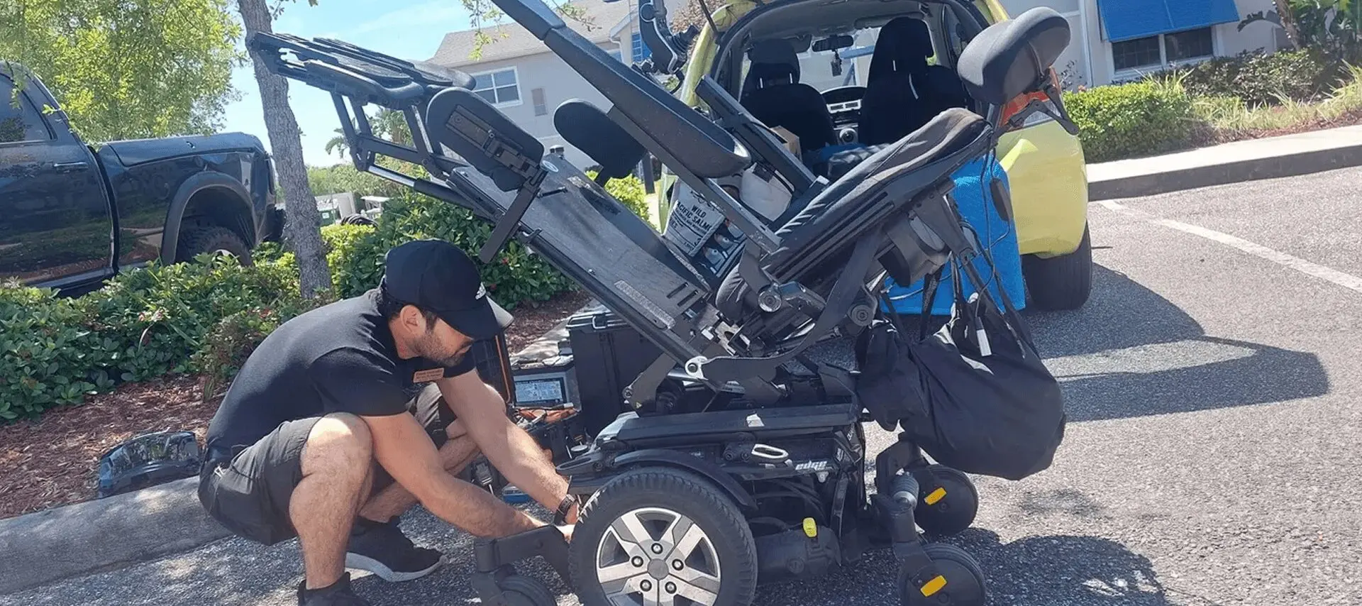 Man adjusting electric wheelchair by car.