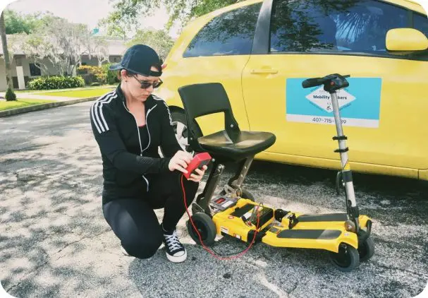 image-4 Person charging mobility scooter by yellow car.